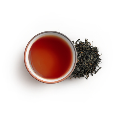Tea cup with red tea and a pile of black tea leaves